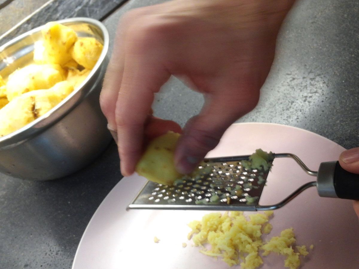 Ginger is being grated with a hand grater.