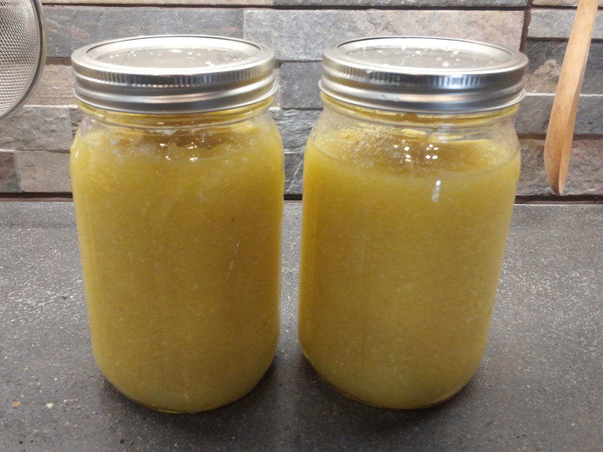 Two mason jars full of a yellowish mixture of ginger and sugar. The jars are sealed with metal lids
