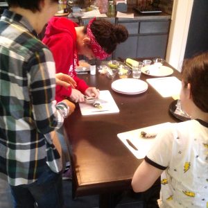 Students cutting California sushi rolls into slices.