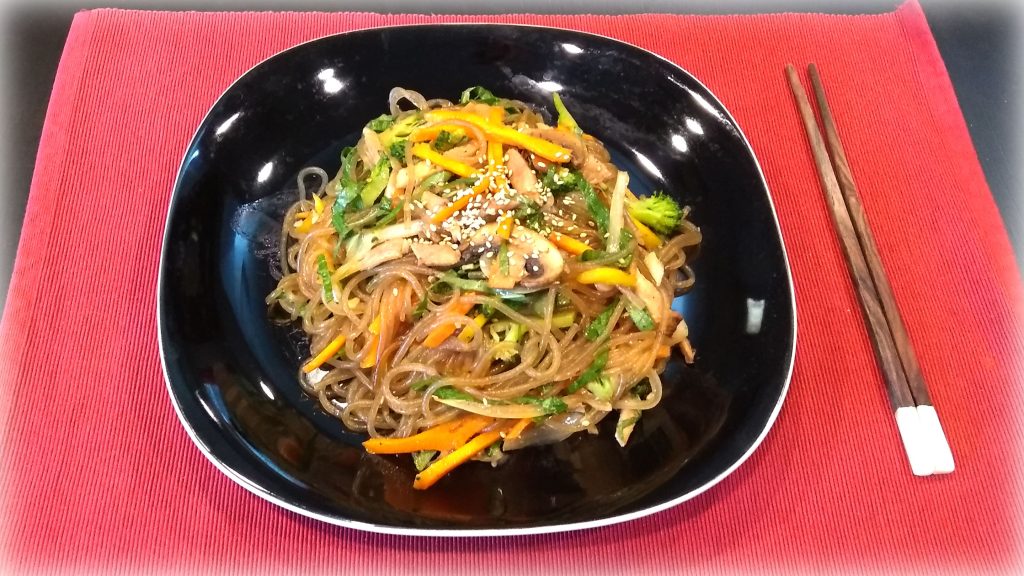 JapChae (잡채) - Korean Stir-fried Sweet Potato Noodles - Dish served with vegetables, meat and sesame seeds for garnish