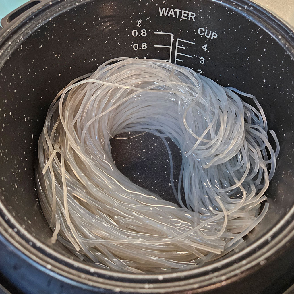 Japchae Noodles in rice cooker. Soaked in water to soften.